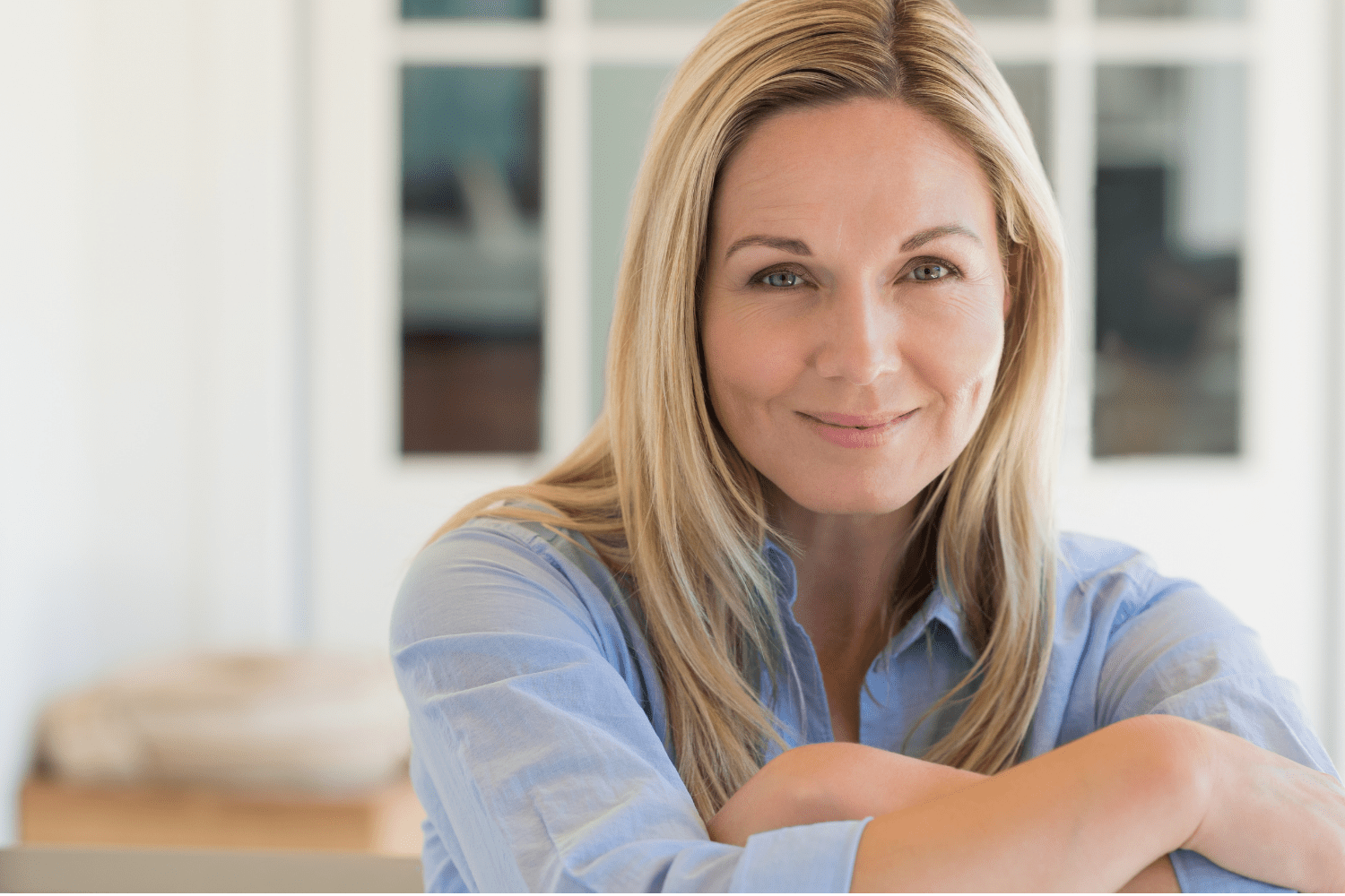 Smiling woman sitting indoors, arms folded